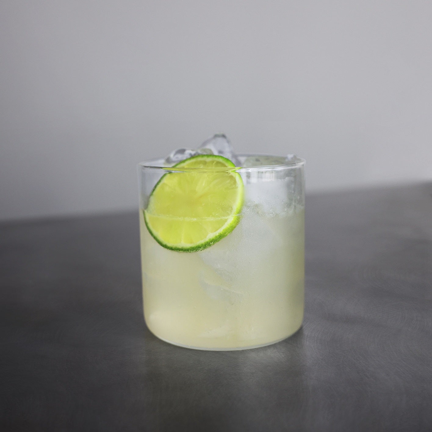 Cilantro Sour in a rocks glass with a lime wheel