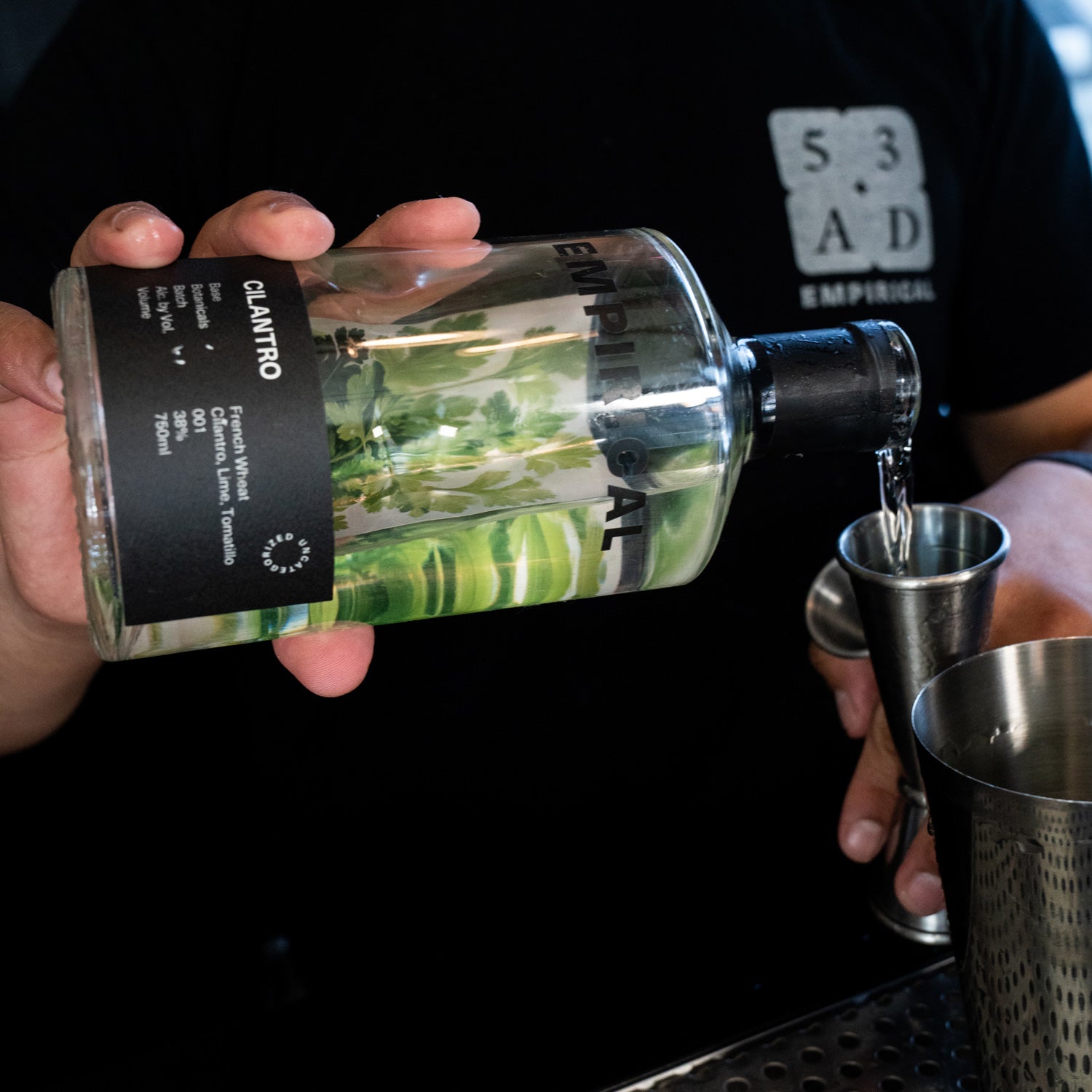 Bartender pouring Empirical Cilantro from the bottle into a jigger at a 53AD event