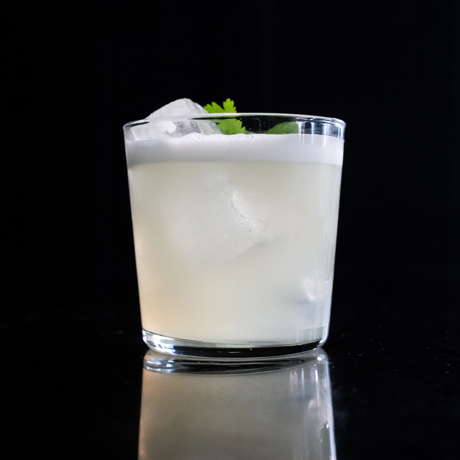 Cilantro sour in a rocks glass with cilantro leaf garnish