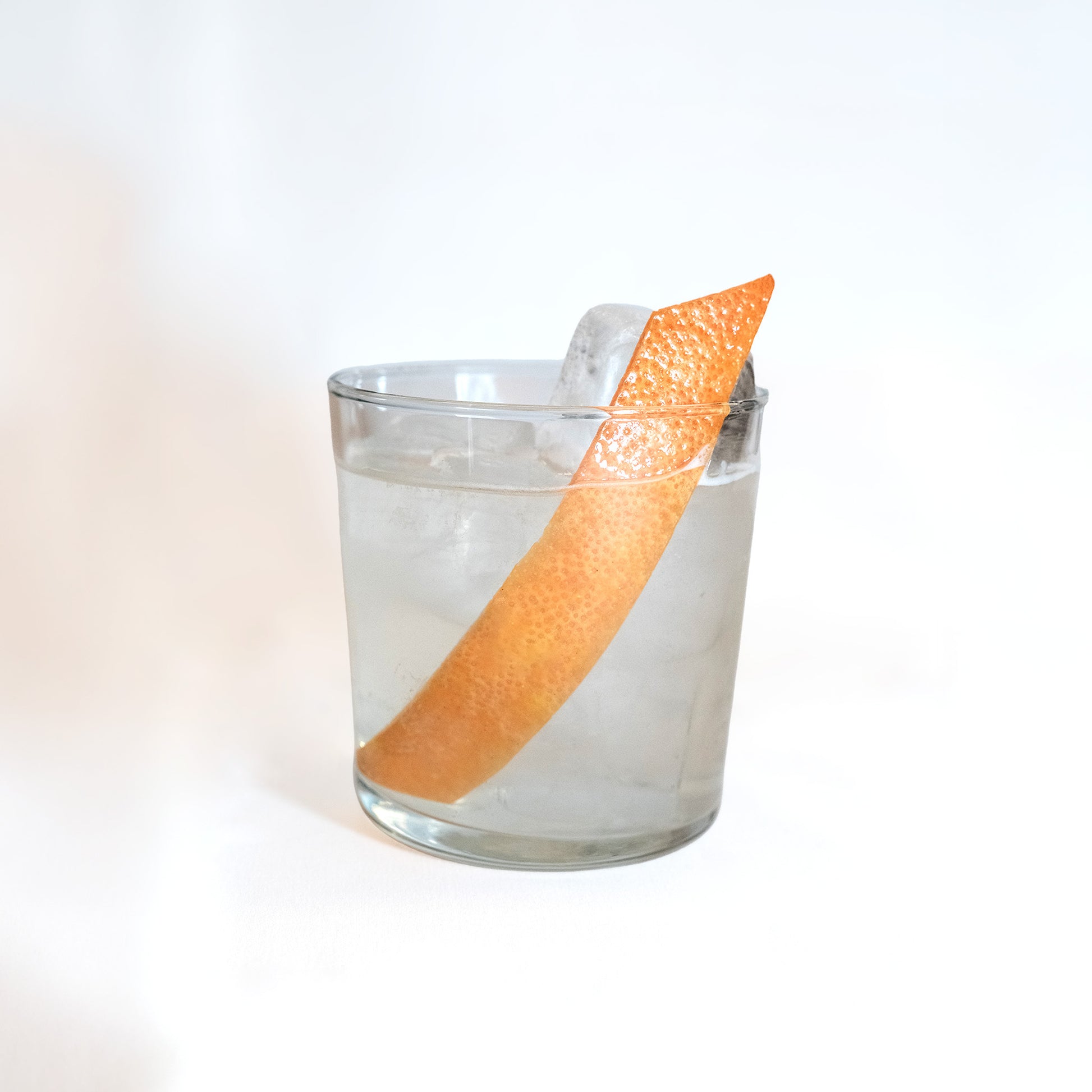 Empirical Stonefruit highball in a rocks glass with long grapefruit peel garnish