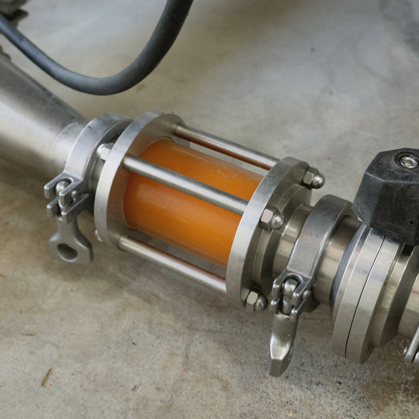 Glowing orange Doritos-infused spirit visible in a stainless distillation rig