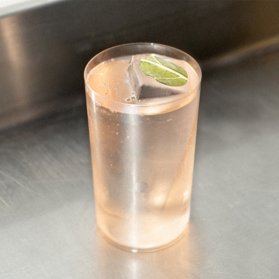 Symphonic cocktail in a tall glass with lime wheel on a steel surface