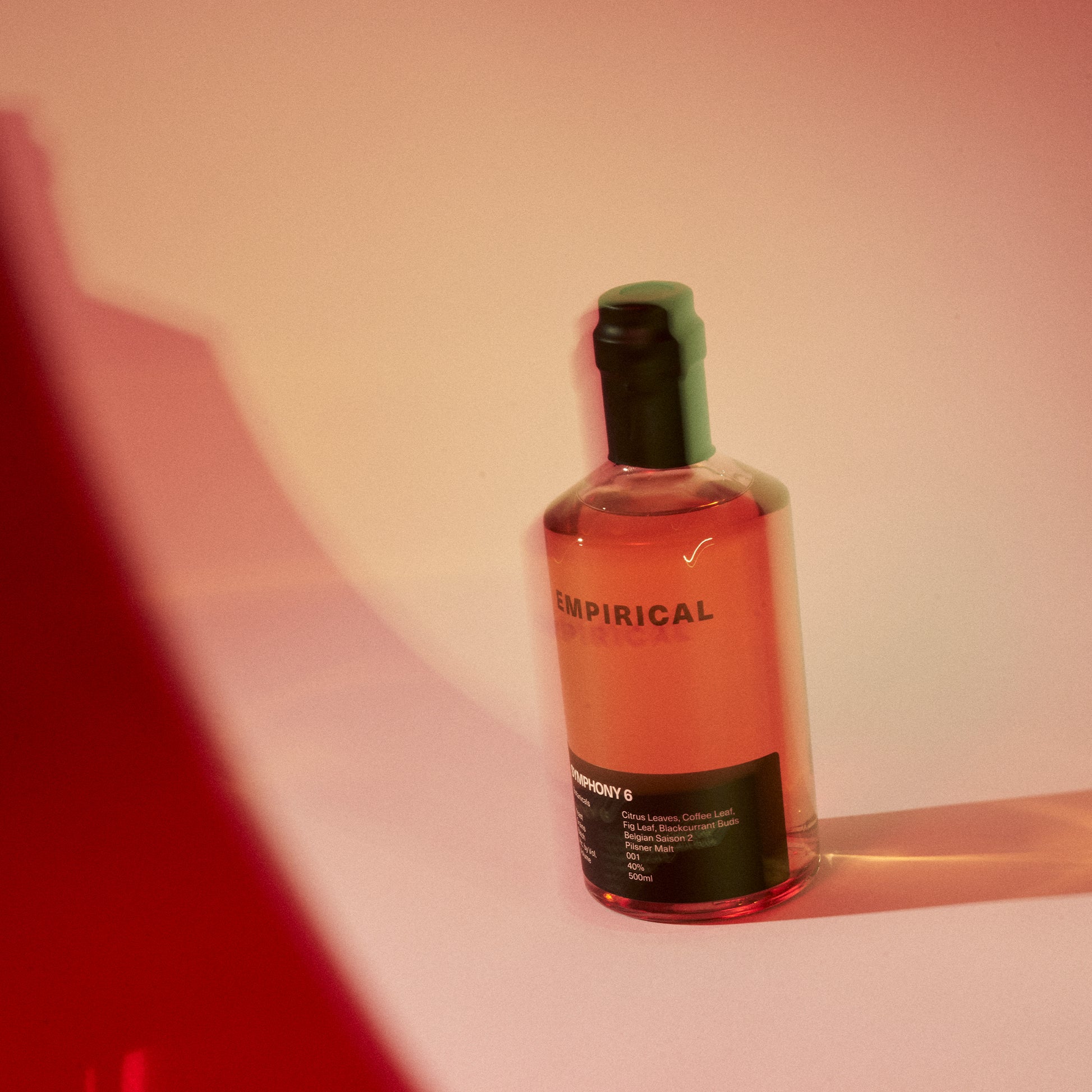 Empirical Symphony 6 bottle on a pink set with red light slash