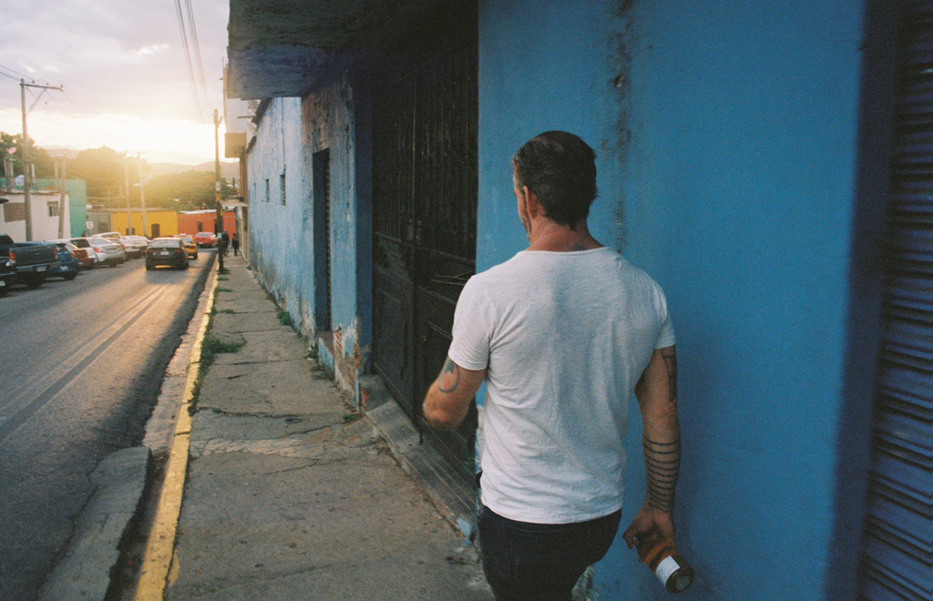 Person walking past a blue wall on a Mexican street at sunset, near where Ayuuk is sourced